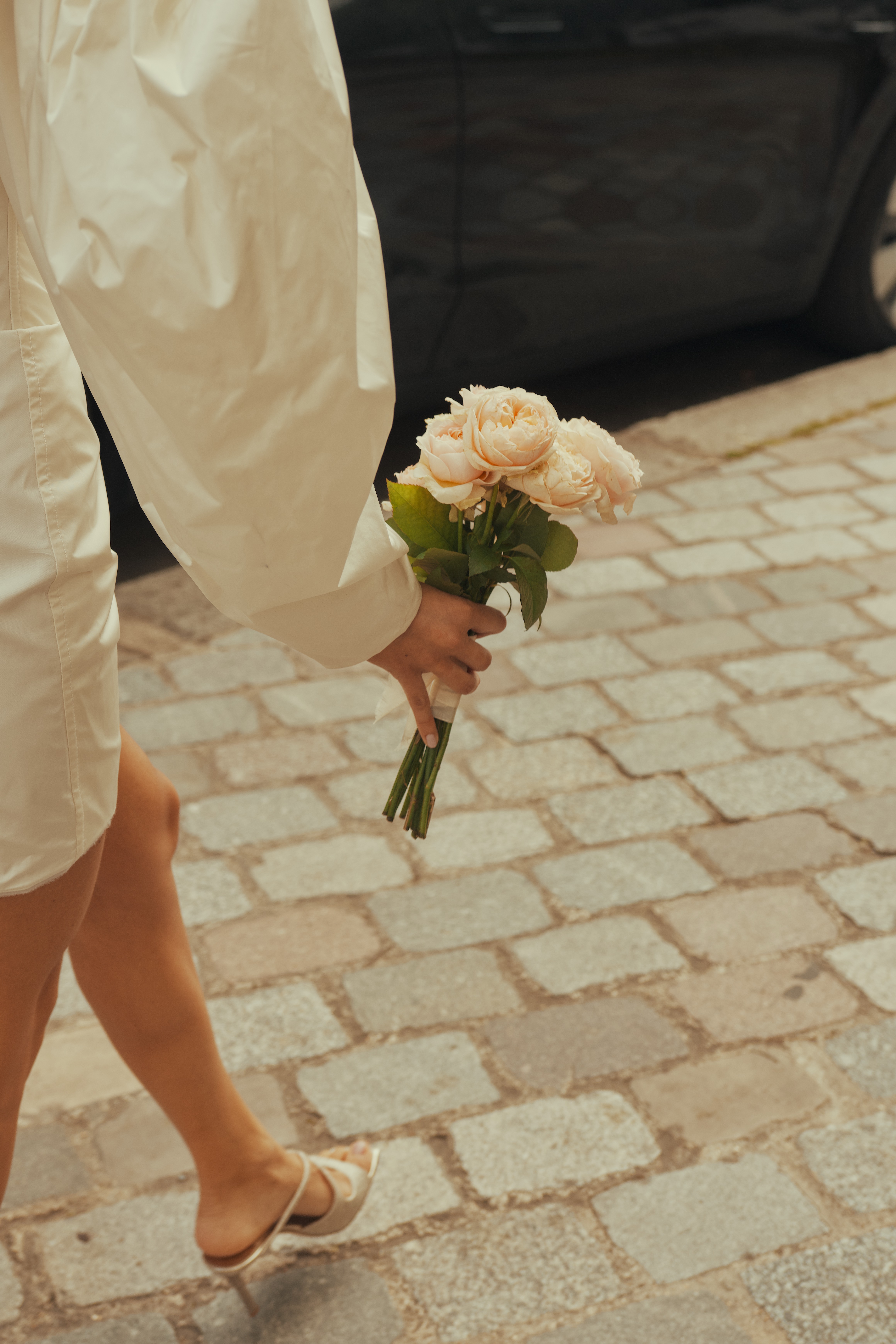 Bouquet de mariage tenu par une mariée sur des pavés